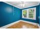 Bedroom featuring bold blue walls, hardwood floors, a ceiling fan, and a bright window with natural light at 500 Peigler Nw St # Lots 1 & 2, Concord, NC 28027