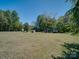Expansive backyard featuring lush green grass, mature trees, and play structures at 55 Dixie Dr, Taylorsville, NC 28681