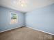 A bedroom with soft blue walls, neutral carpeting, a bright window, and ample natural light at 55 Dixie Dr, Taylorsville, NC 28681