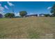 Expansive lawn leads up to a single-story house and shelter on a sunny day with trees dotting the landscape at 55 Dixie Dr, Taylorsville, NC 28681
