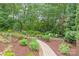 Landscaped backyard with a brick path, lush greenery, and mature trees for added privacy at 6831 Conservatory Ln, Charlotte, NC 28210