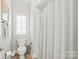 Small bathroom featuring toilet, window with shutters and tiled shower with curtain at 6831 Conservatory Ln, Charlotte, NC 28210