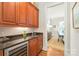 Wet bar with wooden cabinets, granite countertop, wine refrigerator, and view to dining room at 6831 Conservatory Ln, Charlotte, NC 28210
