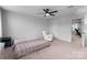 A neutral-toned bedroom featuring a ceiling fan, natural light and a comfortable sitting chair at 703 Pointe Andrews Dr, Concord, NC 28025