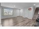 Bright living area featuring laminate flooring, neutral paint, a large window, and multiple entryways at 703 Pointe Andrews Dr, Concord, NC 28025