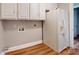 Functional laundry area with white cabinets, appliances, and wood-look flooring at 7101 City View Dr, Charlotte, NC 28212
