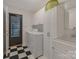 Bright laundry room features checkerboard floors, washer, sink, ample white storage cabinets, and outdoor access at 7312 Barcliff Dr, Charlotte, NC 28212