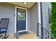 Close-up of the home's front door, featuring a rocking chair, stylish landscaping, and gray siding at 8024 Eagle St, Mount Pleasant, NC 28124