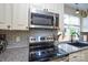 This kitchen range features stainless steel appliances, white cabinets, and subway tile backsplash at 8024 Eagle St, Mount Pleasant, NC 28124