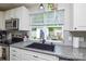 This kitchen sink features white cabinets, gray counters, a black sink, and backyard views at 8024 Eagle St, Mount Pleasant, NC 28124