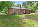 Exterior view of the brick house, showcasing the backyard with trees and a covered patio area at 804 Gw Broome Rd, Monroe, NC 28112