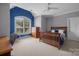 Bright bedroom with blue accent wall, a ceiling fan, and a large window with natural light at 8701 Highgrove St, Charlotte, NC 28277