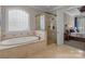 Bathroom featuring a soaking tub, glass-enclosed shower, and access to the main bedroom at 8701 Highgrove St, Charlotte, NC 28277