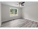 Bright bedroom featuring a ceiling fan, large window, and stylish gray wood-look flooring at 894 Oval St, Kannapolis, NC 28081