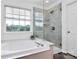 Luxurious bathroom featuring a large window, soaking tub, and frameless shower at 9157 Snow Hill Ct, Charlotte, NC 28269