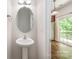 Neat powder room featuring a pedestal sink, oval mirror, and view into the kitchen and outdoor deck at 9203 Grand Valley Dr, Charlotte, NC 28213
