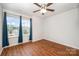 Well-lit bedroom featuring hardwood floors, a ceiling fan, and a sunlit window with blue curtains at 9203 Grand Valley Dr, Charlotte, NC 28213