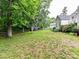 Expansive, grassy backyard with mature trees and partial fencing, perfect for outdoor activities and privacy at 11647 Baystone Pl, Concord, NC 28025