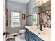 Bathroom with blue vanity, patterned tile flooring, and a framed window at 11647 Baystone Pl, Concord, NC 28025