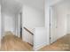 Bright hallway with wood-look floors leading to various rooms and stairs with wood handrail at 12744 Susanna Dr, Charlotte, NC 28214