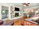 Inviting living room featuring built-in bookshelves, a fireplace, hardwood floors, and a ceiling fan at 14027 Springwater Dr, Matthews, NC 28105