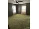 This bedroom offers ample space, green carpeting, and two large windows for natural light at 208 E Main St, Cleveland, NC 27013