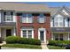 Charming red brick townhome featuring blue shutters, manicured bushes, and a welcoming front door at 2147 Lake Breeze Ln, Denver, NC 28037