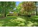 Overgrown backyard featuring mature trees, a lush lawn, a home, and storage shed at 232 Scottridge Dr, Charlotte, NC 28217