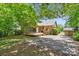 View of the home's backyard featuring a back patio, driveway, brick facade, and manicured lawn at 232 Scottridge Dr, Charlotte, NC 28217