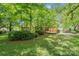 Landscaped backyard with mature trees, lush lawn, and a home with a back patio at 232 Scottridge Dr, Charlotte, NC 28217