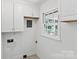Bright laundry room with white cabinets, a utility sink, and a window providing natural light at 232 Scottridge Dr, Charlotte, NC 28217