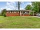 Charming red brick home featuring a cozy front porch and a convenient carport with a well-maintained lawn at 2885 Wright Ave, Salisbury, NC 28147