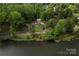 Aerial view of a home with lush landscaping, a detached garage, and serene pond views at 5100 Crestland Ave, Charlotte, NC 28269