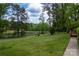 Expansive grassy backyard featuring mature trees and a tranquil pond view, creating a serene outdoor setting at 5100 Crestland Ave, Charlotte, NC 28269