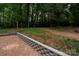 Backyard view featuring a brick patio with retaining wall and access to the wooded area at 5100 Crestland Ave, Charlotte, NC 28269