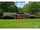 Ranch-style home featuring a large front yard, mature trees, a red brick facade, and a wooden porch at 5100 Crestland Ave, Charlotte, NC 28269