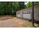 Detached two-car garage with white doors, exterior lighting, and ample parking on a gravel driveway at 5100 Crestland Ave, Charlotte, NC 28269