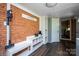 A mudroom with brick walls, hardwood floors, storage cubbies, coat rack, and a white paneled door at 5100 Crestland Ave, Charlotte, NC 28269
