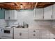 View of basement kitchen featuring white cabinets, white appliances and a white subway tile backsplash at 5873 Alexis Ln, Vale, NC 28168