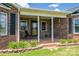Charming front porch with brick and stone features a swing and is framed by landscaped flower beds at 5873 Alexis Ln, Vale, NC 28168