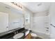 Well-lit bathroom featuring a black granite countertop, a tub with white enclosure, and wood-look flooring at 668 Smith St, Kannapolis, NC 28083