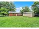 Large, grassy backyard with a brick house, detached garage, and a fire pit, ideal for outdoor activities and gatherings at 7412 Woodstream Dr, Charlotte, NC 28210