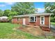 Rear exterior view of brick house, showcasing patio, door, bay window, and well-maintained yard at 7412 Woodstream Dr, Charlotte, NC 28210