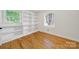 Well-lit bedroom with built-in shelving, beautiful hardwood floors, and natural light streaming through the windows at 7412 Woodstream Dr, Charlotte, NC 28210
