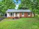 Charming single-story home featuring a brick facade, well-maintained lawn, and mature trees at 7412 Woodstream Dr, Charlotte, NC 28210