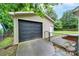 Detached garage features a black door, adjacent access gate, and concrete driveway at 7412 Woodstream Dr, Charlotte, NC 28210