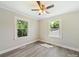 An empty, well-lit bedroom with two windows, ceiling fan, and neutral walls at 83 Woodsdale Se Pl, Concord, NC 28025