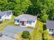 Charming single-story home with a bright red door and gravel driveway surrounded by lush greenery at 83 Woodsdale Se Pl, Concord, NC 28025