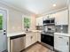 Modern kitchen featuring stainless steel appliances, white cabinetry, and a window with a view of greenery at 83 Woodsdale Se Pl, Concord, NC 28025