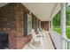 Relaxing covered porch with brick accents, white rocking chairs, and views of the expansive yard at 8520 Wright Rd, Kannapolis, NC 28081